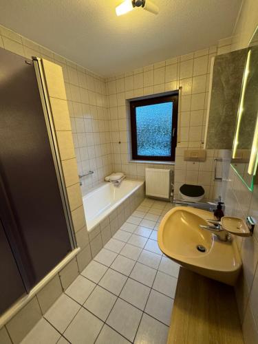 een badkamer met een wastafel en een bad bij Ferienhaus im Maadebogen in Wilhelmshaven