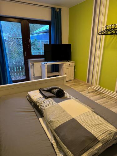 een slaapkamer met een bed, een tv en een raam bij Ferienhaus im Maadebogen in Wilhelmshaven