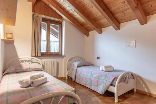 2 Betten in einem Zimmer mit Holzdecken in der Unterkunft Lo scrigno del lago Molveno Trento in Molveno