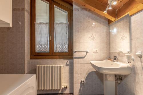 ein Bad mit einem Waschbecken, einem WC und einem Fenster in der Unterkunft Lo scrigno del lago Molveno Trento in Molveno