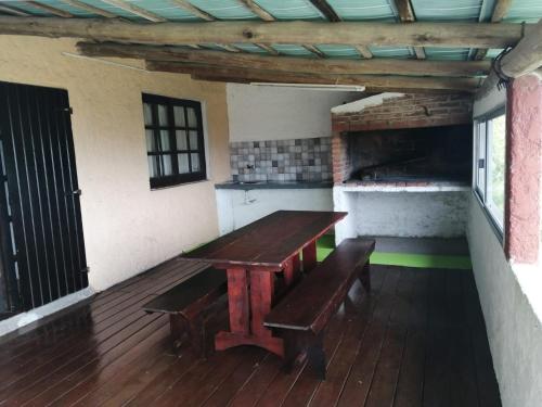 uma mesa de madeira e bancos num deque em Cabaña Jacarandá em Villa Serrana