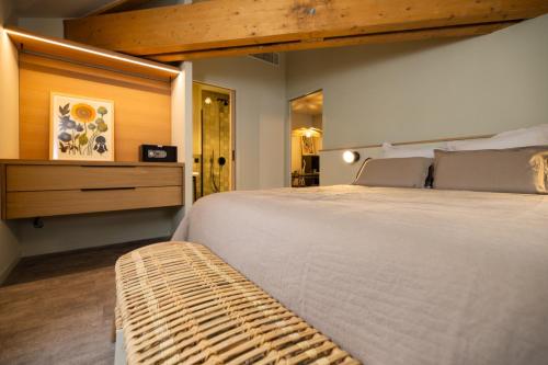 a bedroom with a large white bed and a bench at La Villa Serra - Appartements in Agen