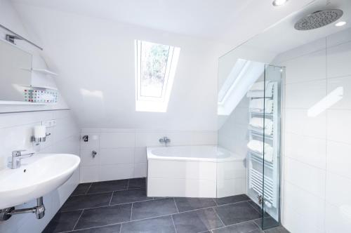 a white bathroom with a sink and a bath tub at Haus an der Haslach in Lenzkirch