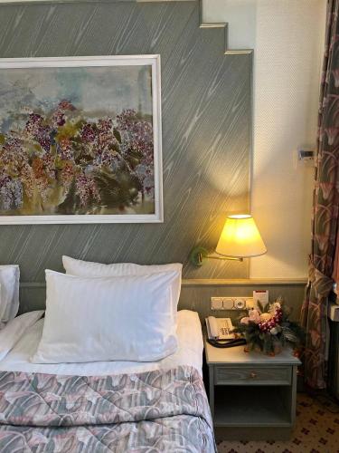 a bed in a hotel room with a painting on the wall at Natsionalny Hotel in Kyiv