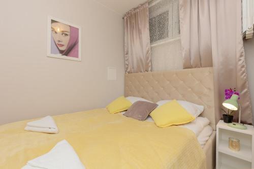 a bedroom with a bed with yellow and white pillows at Rajska Łodź One Bedroom & Balcony by Renters in Łódź