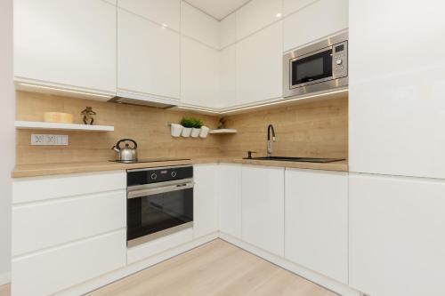a kitchen with white cabinets and a microwave at Rajska Łodź One Bedroom & Balcony by Renters in Łódź