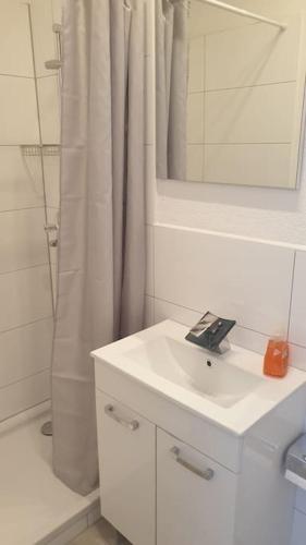 a bathroom with a sink and a shower with a mirror at Ferienwohnung in Bochum