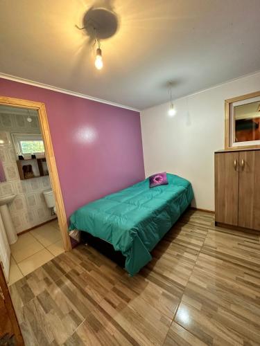 1 dormitorio con cama verde y pared morada en Habitación con baño privado, 