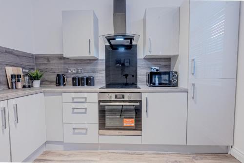 a kitchen with white cabinets and a stove top oven at Modern 3-Bedroom Townhouse - Free Secure Parking - Jewellery Quarter in Birmingham