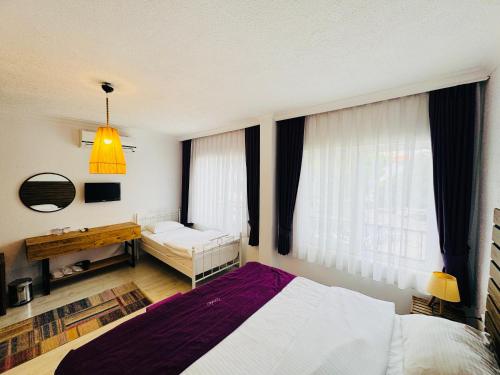 a bedroom with two beds and a desk and a window at Fuda Hotel in Datca
