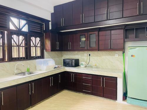 a kitchen with wooden cabinets and a sink and a refrigerator at Sri Mali Holiday Home in Pelena