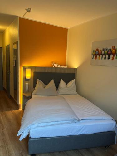 - une chambre avec un grand lit et des draps blancs dans l'établissement Hotel am Stadtpark, à Hilden