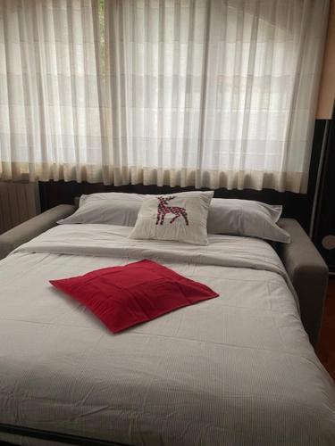 Una cama blanca grande con una almohada roja. en Mountain Apartments Tarvisio en Tarvisio