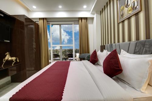 um quarto com uma cama grande e almofadas vermelhas e brancas em Limewood Stay Diamond 2BHK & Studio Huda City Centre & FORTIS em Gurgaon