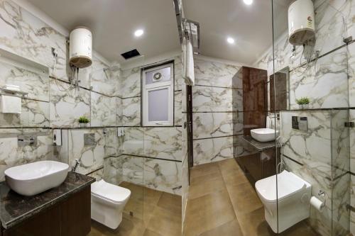 uma casa de banho com 2 WC e uma cabina de duche em vidro. em Limewood Stay Diamond 2BHK & Studio Huda City Centre & FORTIS em Gurgaon