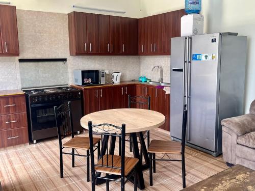 a kitchen with a table and a stainless steel refrigerator at Kijani Kibichi Cottages in Naro Moru