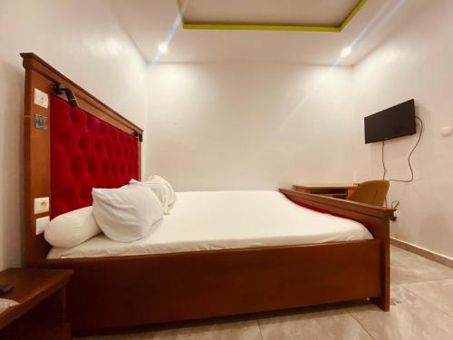 a small bedroom with a bed with a red headboard at Charme Urbain de Douala in Douala