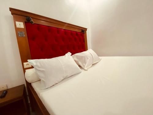a white bed with a red headboard and two white pillows at Charme Urbain de Douala in Douala
