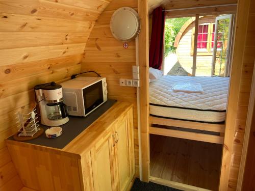 une petite maison avec un four micro-ondes et un lit dans l'établissement TONNEAU HERBERGEMENT INSOLITE AU CAMPING DES NIERES, à Ébreuil