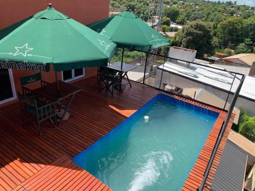 eine Terrasse mit einem Pool und einem grünen Sonnenschirm in der Unterkunft Wicz Apart Iguazú in Puerto Iguazú