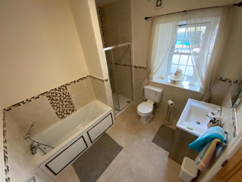 y baño con bañera, aseo y lavamanos. en Portinaghy House, en Scairbh na gCaorach