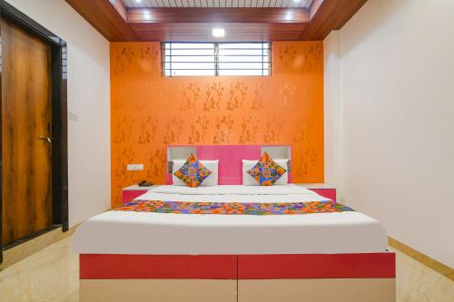 1 dormitorio con 1 cama con pared de color naranja en FabExpress Dream paradise, en Indore