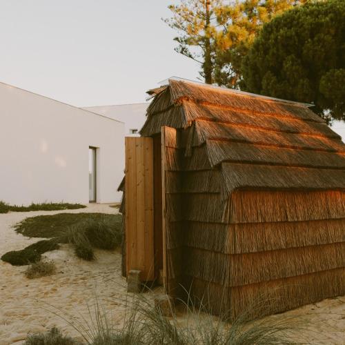 a wooden shed sitting in the sand next to a building at Casa Modesta in Olhão