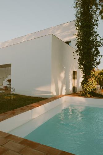 a swimming pool in front of a white house at Casa Modesta in Olhão