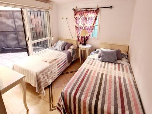 two beds in a room with a window at Marbella apartamento en Malaga in Málaga