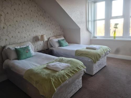 1 dormitorio con 2 camas y ventana en Victoria Hotel, en Portknockie