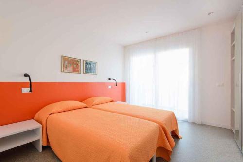 - une chambre avec un lit orange et une fenêtre dans l'établissement Apartment in Lignano Sabbiadoro 21778, à Lignano Sabbiadoro