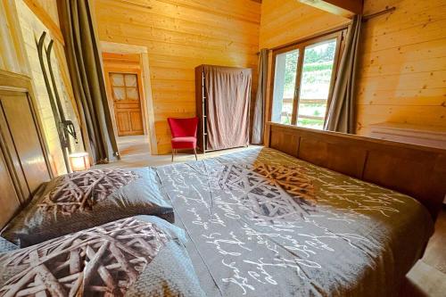 1 dormitorio con 1 cama y 1 silla roja en una cabaña en Peaceful chalet near the ski slopes 8 people, en Fontrabiouse