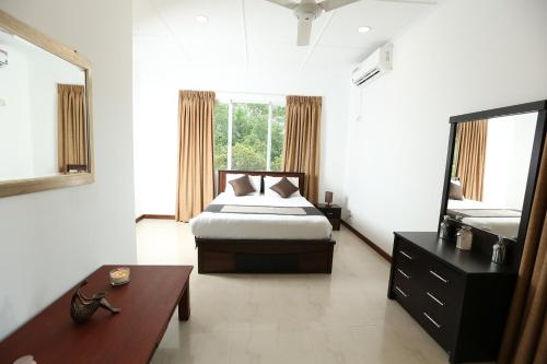 a bedroom with a bed and a table and a window at Eden Gardens Residence in Hokandara South