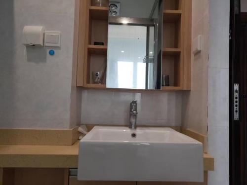 Yangzhou Xianyun Apartment في يانغتشو: حمام مع حوض أبيض ومرآة