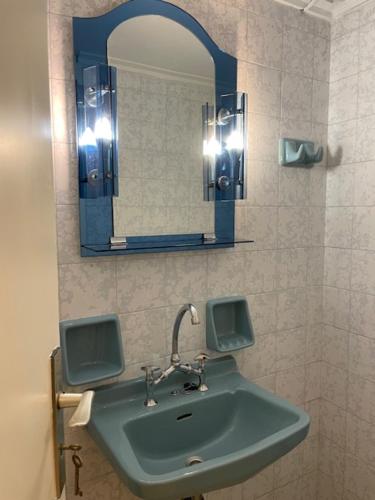 ein Badezimmer mit einem grünen Waschbecken und einem Spiegel in der Unterkunft Athens Faliro Beach Residence in Athen