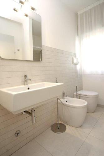 a white bathroom with a sink and a toilet at Dune Dependance in Bibione