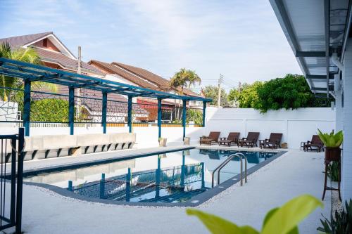 a swimming pool with chairs and tables next to a building at Singharaj Boutique Hotel in Chiang Mai