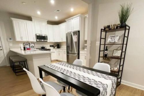 uma cozinha com uma mesa com cadeiras brancas e um balcão em New 3BR condo near IAD airport weekly and monthly discount em Herndon