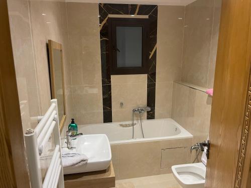 a bathroom with a sink and a tub and a toilet at Appartement luxe a tunis jardin de Carthage in Al Karm