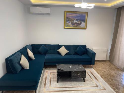 a blue couch in a living room with a table at Appartement luxe a tunis jardin de Carthage in Al Karm