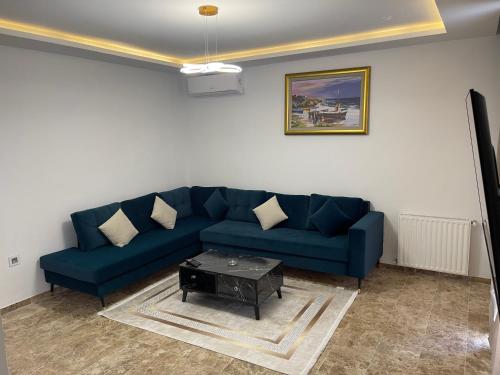 a living room with a blue couch and a table at Appartement luxe a tunis jardin de Carthage in Al Karm