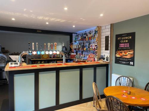 eine Bar in einem Restaurant mit einem Tisch und Stühlen in der Unterkunft The Fishmongers Tavern in Sheringham