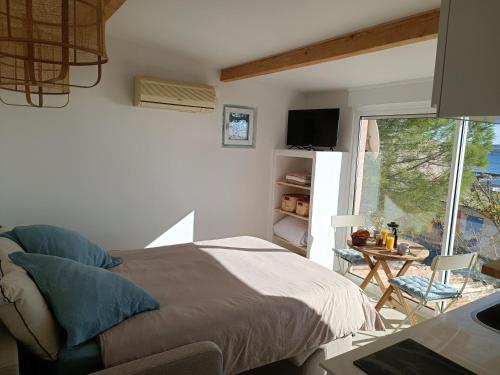 Schlafzimmer mit einem Bett, einem Tisch und einem Fenster in der Unterkunft "La Cabane de Thau" avec vue imprenable sur Sète in Loupian