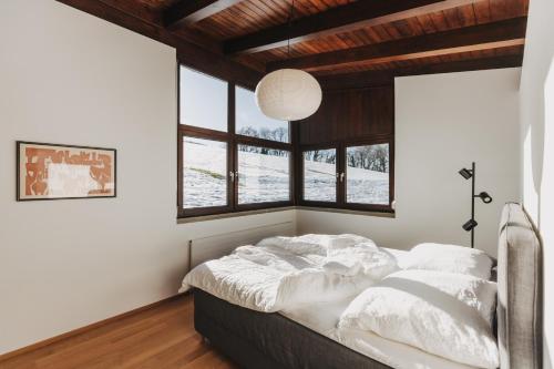 sypialnia z łóżkiem z białą pościelą i oknami w obiekcie Haus A Ankommen-Abschalten-Auftanken w Bregencji