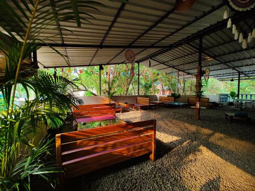 einen Pavillon mit Holzbänken in einem Zimmer mit Pflanzen in der Unterkunft THE MUSAFIR HOSTEL in Anjuna