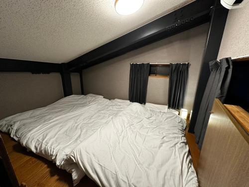 a bedroom with a white bed with a black headboard at AYA-KAMOJIMA in Yoshinogawa