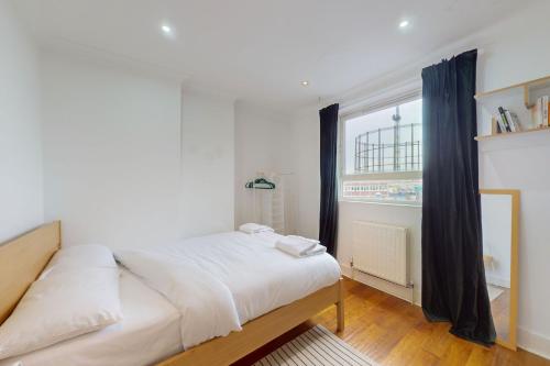a bedroom with a white bed and a large window at Cozy 2 Bedroom Flat in Cambridge Heath in London