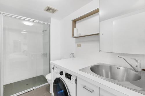 a white bathroom with a sink and a washing machine at South bank Serviced Apartments in Brisbane