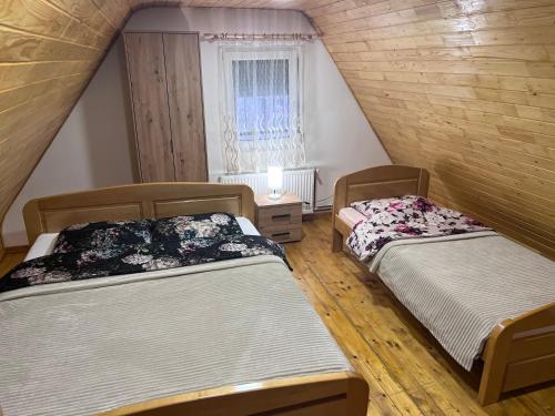 two beds in a attic room with a window at Vikendica Martinović in Divčibare