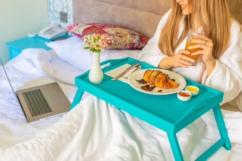 a woman sitting on a bed with a table with a plate of food at Sahil Inn Baku Hotel Formula 1 View in Baku